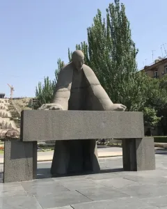 Monument to Alexander Tamanyan in a paved plaza, with a large stone staircase rising behind it.