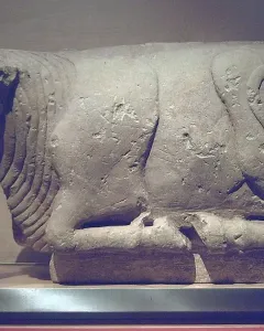 Bull of Osuna stone sculpture shown in profile on a white plinth.