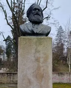 Karl Marx Monument showing a dark bust of a bearded man on a tall stone pedestal.