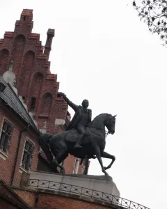 Tadeusz Kościuszko Monument, a dark equestrian statue of a man in a long coat with one arm raised, against a bright overcast sky.