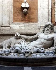 Marforio, a white marble reclining river god with a bearded upper body, set in an architectural niche.