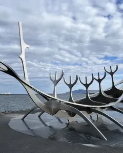 The Sun Voyager sculpture beside calm water under a cloudy sky.