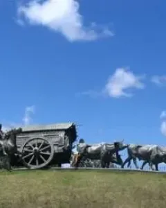 Monument to the Cart sculpture showing a covered cart pulled by oxen with a rider on horseback nearby.