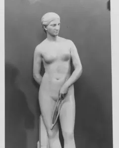 Marble statue of a nude woman standing on a round base and holding a looped rope.