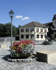 Anscavallo, a large abstract equine sculpture on a paved square with flower planters and streetlamps nearby.