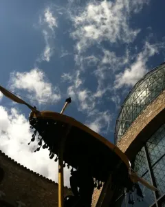 Rainy Taxi suspended between stone buildings and a glass dome under a blue sky.