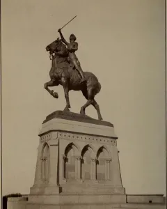 Joan of Arc equestrian statue with an armored figure raising a sword on a rearing horse atop a tiered stone pedestal.