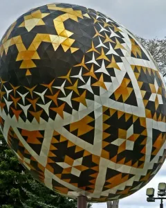 Vegreville pysanka egg sculpture with geometric black, gold, and white patterns outdoors.