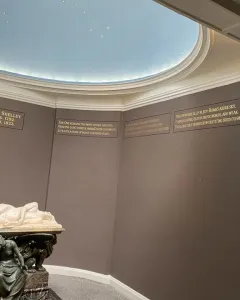 Shelley Memorial with a white marble reclining male figure on a sarcophagus, supported by a seated bronze figure.