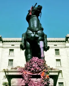 Equestrian statue of Francisco Franco on a stone pedestal with a flower wreath at the base.