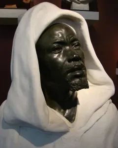 Salem, Negro of Sudan, a dark metal bust of a bearded man in a white hooded garment.