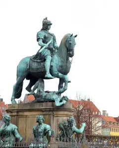 Christian V equestrian statue showing an armored rider on a rearing horse atop an ornate pedestal with sculptural figures.