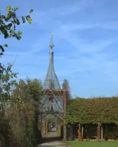 The Green Cathedral vine-covered archway with a path leading through it beside a dense hedge and benches.