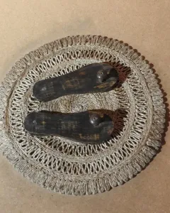 Paduka wooden sandals displayed on a woven mat.