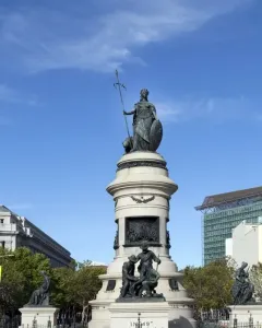 Pioneer Monument in San Francisco, with a bronze crowned female figure atop a tall stone column, sculptural groups at the base, and a fenced foreground.