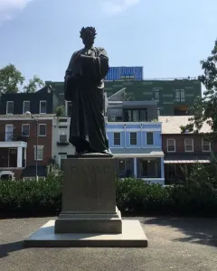Dante Alighieri statue in robes with a laurel wreath, holding a book on a pedestal labeled DANTE.