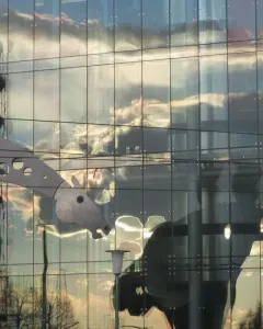 S-Printing Horse sculpture reflected in a glass building at sunset