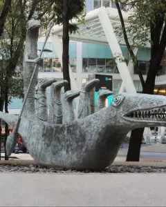 How Doth the Little Crocodile sculpture with a metallic reptile head and smaller figures inside.