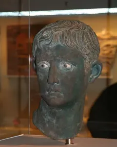 Meroë Head bronze sculpture with a weathered green patina and inlaid eyes.