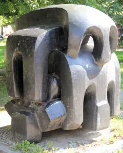 Treblinka abstract sculpture with blocky dark forms and carved openings in a paved outdoor setting.