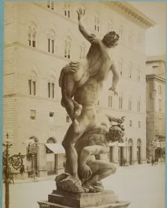 Giambologna’s Rape of the Sabine Women sculpture in a public square, with three intertwined figures against a building with arched windows.