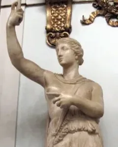 Marble statue of a wounded Amazon standing with one arm raised and a short tunic.