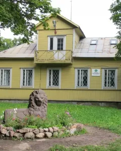 Recumbent lion statue in a flower bed beside a yellow building in Monrepos Park