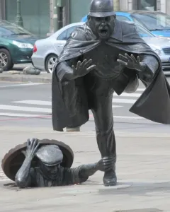 Vaartkapoen bronze sculpture showing a policeman being grabbed by a figure emerging from a manhole.