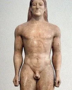 Kroisos Kouros, a front-facing ancient marble statue of a nude young man with braided hair, standing with one leg forward.