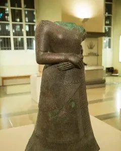 Headless statue of Napir-Asu with hands clasped at the waist and an intricately decorated long garment.