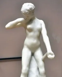 Standing Fauness, a white marble nude female sculpture with her head bowed, one hand at her neck and the other holding a downward-pointing club.