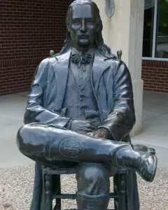 Wild Bill Hickok Memorial statue of a seated man with long hair, a mustache, and a bow tie