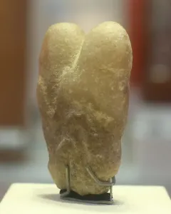 Ain Sakhri Lovers stone sculpture with two rounded lobes on a dark base.