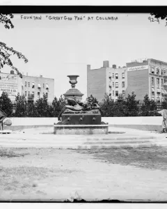 The Great God Pan fountain with a reclining figure and central urn ornament in a grassy area.