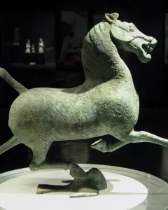 Flying Horse of Gansu bronze horse sculpture balanced on one hoof atop a bird on a display stand