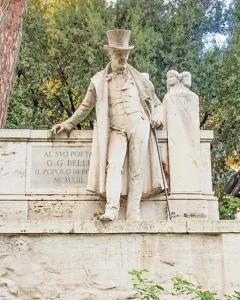 Monument to Giuseppe Gioachino Belli showing a stone statue of a man in a top hat and long coat leaning on a plinth with a cane.