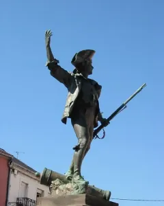 Statue of the Volunteer of 1792, a bronze soldier in a tricorne hat standing on a stone pedestal with one foot on a cannon.
