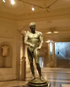 Athlete from Ephesus bronze statue displayed on a pedestal in a grand museum hall.