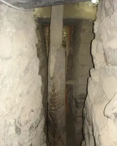 The Lanzón monolith standing in a narrow stone passage, with intricate carvings visible on its surface.