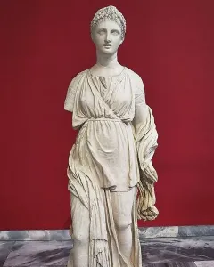 Artemis Diadoumena marble statuette with braided hair and draped garments, missing part of the left arm.