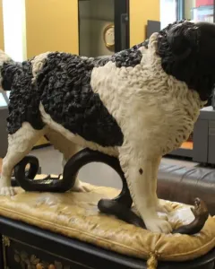 Bashaw, a sculpture of a black and white dog standing with its paws on a coiled snake in a museum display.