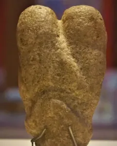 Ain Sakhri Lovers stone sculpture with two rounded lobes on a dark base.