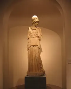 Draped statue of Athena wearing a helmet, standing on a dark pedestal in a recessed arched alcove.
