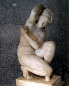 Crouching Venus marble sculpture of a nude female figure in a crouching pose on a base.
