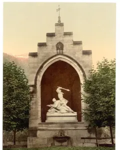 Winkelried Memorial with a stone arch niche framing a white marble sculpture of two figures, set among trees with mountains in the background.