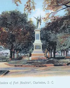The Defenders of Fort Moultrie monument in a tree-filled park, with a tiered stone base and a figure holding a flag on top.
