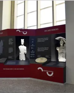 Two Giants of Mont\'e Prama statues displayed in a red and black exhibition stand.