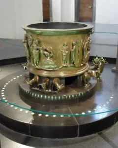 Baptismal font at St Bartholomew\'s Church with bronze relief figures and animal supports.
