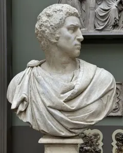 Marble bust of Brutus shown in sharp profile with curly hair and draped clothing.