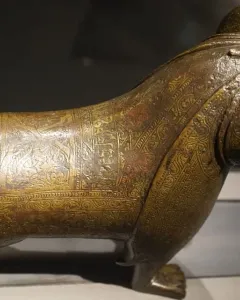 The Lion of Monzon sculpture shown from a three-quarters angle, with engraved decorative patterns across its body.